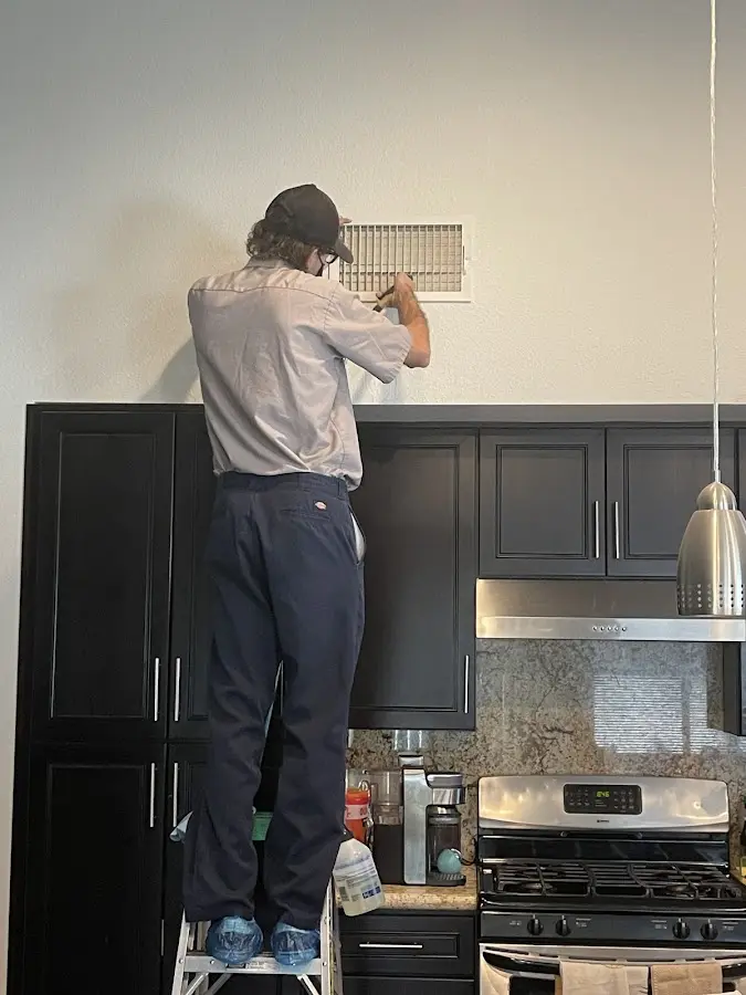 Technician inspecting an air vent during HVAC service in West Windsor